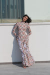 Woman in a floral dress standing on a rooftop with a building in the background